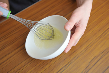 Men's hands whip egg whites to create a cream for baking