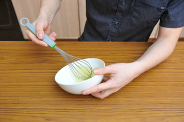Men's hands whip egg whites to create a cream for baking