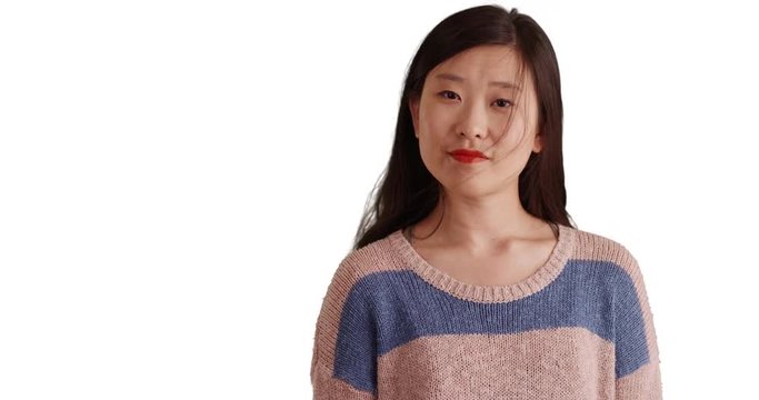 Casual millennial woman looking at camera with blank expression and wearing a sweater on white copyspace, Close-up of Asian female isolated on white background, 4k