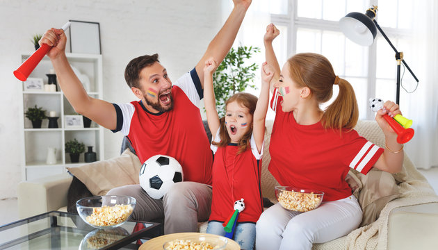 Family Of Fans Watching A Football Match On TV At Home.