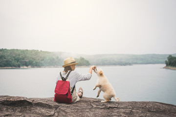 Happy girl playing with little dog in nature background, travel on holiday color of vintage tone and soft focus