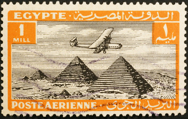 Biplane flying over pyramids in old egyptian postage stamp