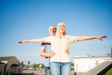 I believe I can fly! Portrait of creative cheerful couple, charming woman holding hands to the side gesturing air plane handsome man holding lover on waist