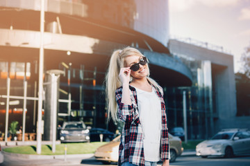 Fototapeta premium Beautiful blond young woman walking on the city street.