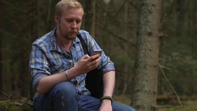 man with a smartphone in the wild forest