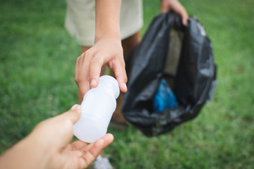 Human hand picking up plastic into bin bag on park ,volunteer concept