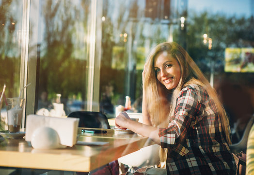 Young Female Student Sitting In Modern Coffe Shop. Sunset.