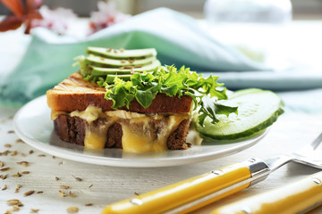 Plate with delicious sandwich on wooden table