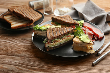 Plate with delicious sandwiches on wooden table
