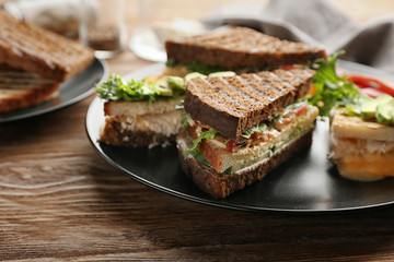 Plate with delicious sandwiches on wooden table