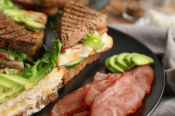 Plate with delicious sandwiches on table, closeup
