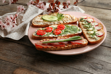 Plate with delicious toasts on wooden table