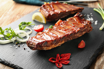 Slate plate with delicious grilled ribs on table