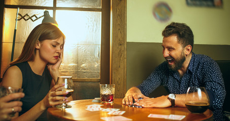 Friends sitting at wooden table. Friends having fun while playing board game.