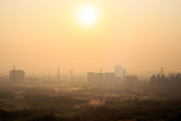 Fototapeta na wymiar Bright sun rising over power lines and morning haze in a Shanghai suburb