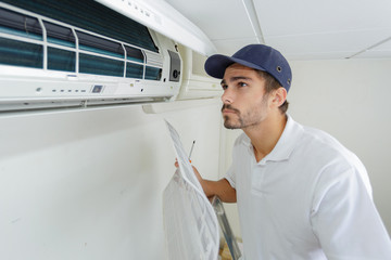 portrait of mid-adult male technician repairing air conditioner