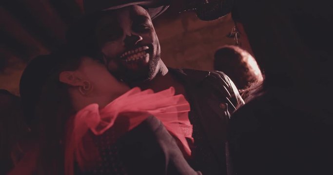 Woman in vampire costume biting man on neck on Halloween