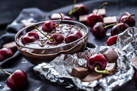 Fresh cherries in bowl with chocolate on dark tablecloth