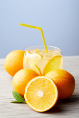 glass of lemonade with oranges on wooden table