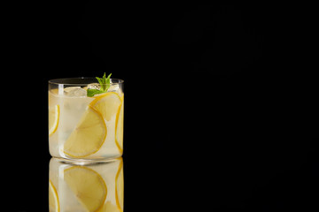 single glass of fresh lemonade on reflective surface isolated on black