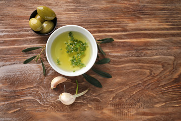 Bowls with oil and olives on wooden table