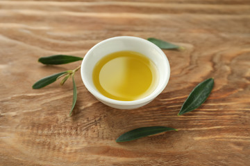 Bowl with fresh olive oil on wooden table