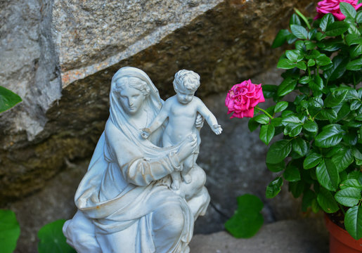 White stone statue of the virgin Mary carrying a baby