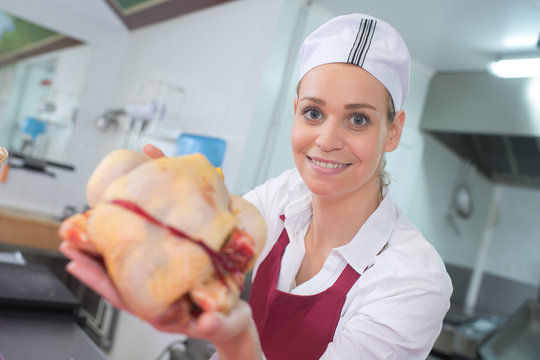 portrait of happy female butcher cutting meat at butchery counter