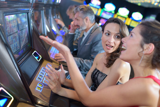 beautiful women in dress playing slot machine