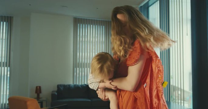 Young mother in red dress spinning around with toddler