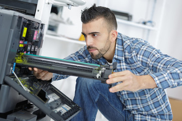 young male technician repairing digital photocopier machine