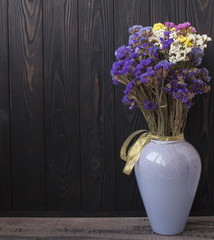 Bouquet of dried wild flowers on a black texture background of vintage wooden planks