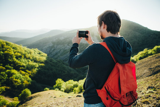 Man taking a photo of the mountains with smartphone.