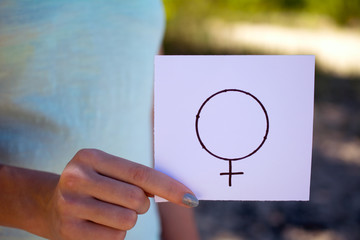 gender definition concept, a piece of paper with a female  symbol in a woman's hand