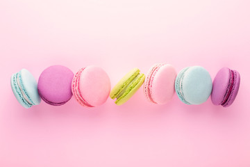 The row of colorful macarons on pink background. Top view.