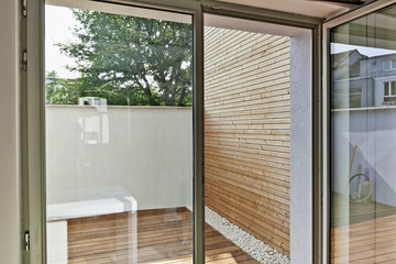 Renovated white ciment wall and insulating wood cladding in outdoor courtyard truth open door...