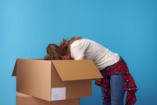 Modern Hipster Looking For Something In Cardboard Box On Blue