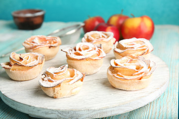 Tasty apple roses from puff pastry on wooden board