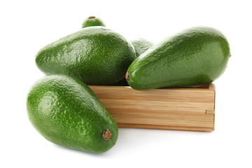 Wooden crate with fresh avocados on white background