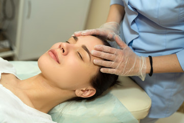 Fototapeta na wymiar beautiful young girl on a facial treatment in a beauty salon doing face massage