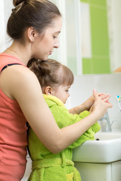 mother washing child toddler hands in bathroom