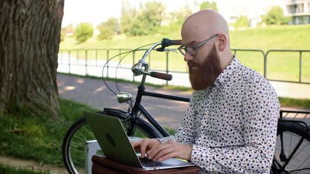Hipster businessman using a laptop outdoors
