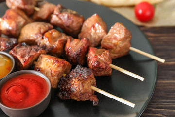 Barbecue skewers with juicy meat and sauces on plate
