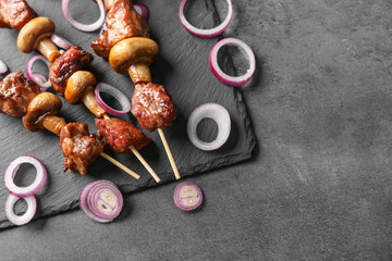 Barbecue skewers with juicy meat and mushrooms on slate plate