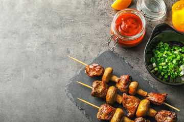 Fototapeta premium Barbecue skewers with juicy meat and mushrooms on slate plate