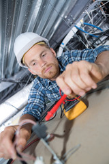 Electrician testing spotlight with multimeter