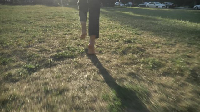 Silhouette of young extraordinary happy bold girl is running on lawn in park in daylight, in summer, heathy lifestyle