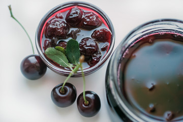 Cherry jam in a bowl and a fresh cherry