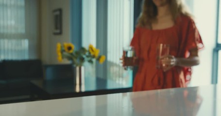 Young woman entering apartment with glasses of water
