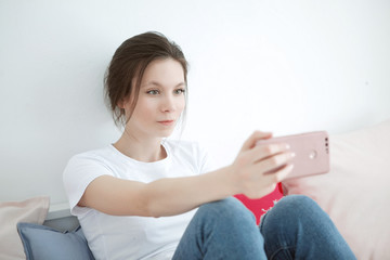 Excited winner checking online the phone for a prize lying on the bed at home with a window in the...